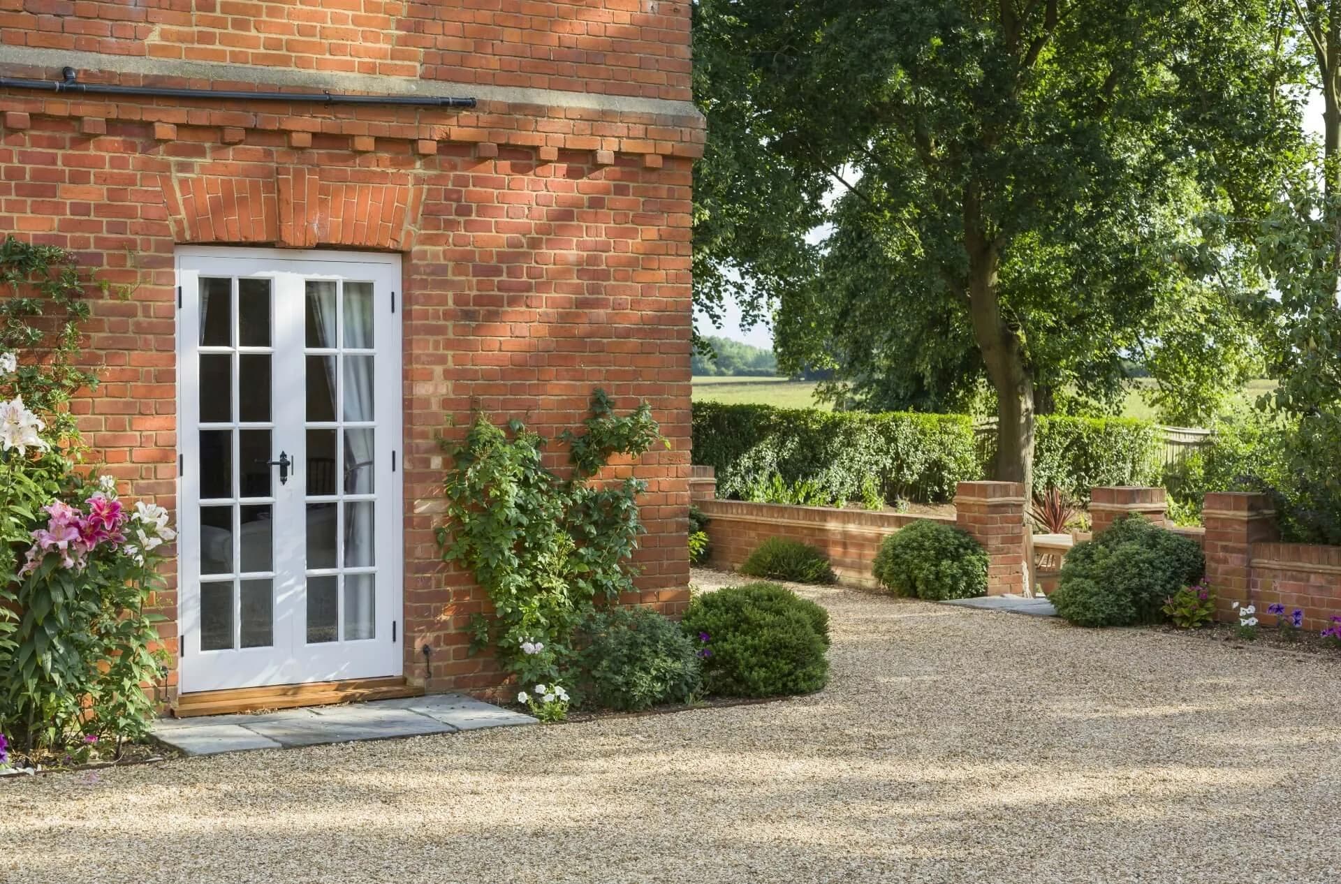 Stone patio against a brick house with white garden doors and planting